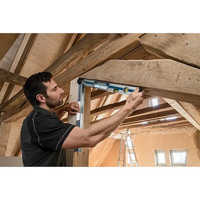 Bosch Professional Digitaler Winkelmesser GAM 270 MFL - Winkel: 0 ° - 270 °, Blattlänge: 60 cm - Ein Handwerker benutzt eine digitale Wasserwaage, um ein Holzbalken in einem Haus zu überprüfen. Das Werkzeug zeigt genaue Messwerte für präzise Bauarbeiten.