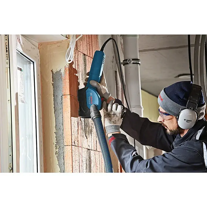 Bosch Professional Absaugvorrichtung GDE 125 EA-T - Passend für: Bosch Winkelschleifer GWS-Serie mit Ø 125 mm - Ein Handwerker benutzt eine Bosch Mauernutfräse, um eine Nut in eine Ziegelwand zu fräsen.