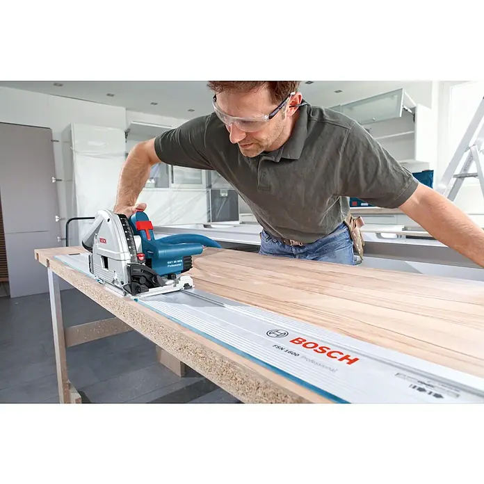 Bosch Professional Führungsschiene FSN 1600 - Länge: 1.600 mm - Ein Mann arbeitet mit einer Bosch GKT 55 GCE Professional Tauchsäge mit Führungsschiene FSN 1600 Professional an einem Holztisch.