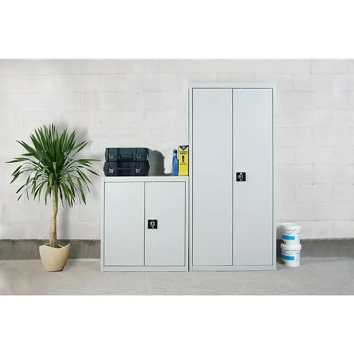 Simonrack Simonlocker Armario multiusos metálico Multi Professional Desmontado - L x An x Al: 40 x 100 x 180 cm, Blanco/Blanco, Número de baldas: 4 ud. - Imagen de un armario metálico plateado de dos puertas, flanqueado por una planta de interior y latas de pintura para almacenamiento adicional.