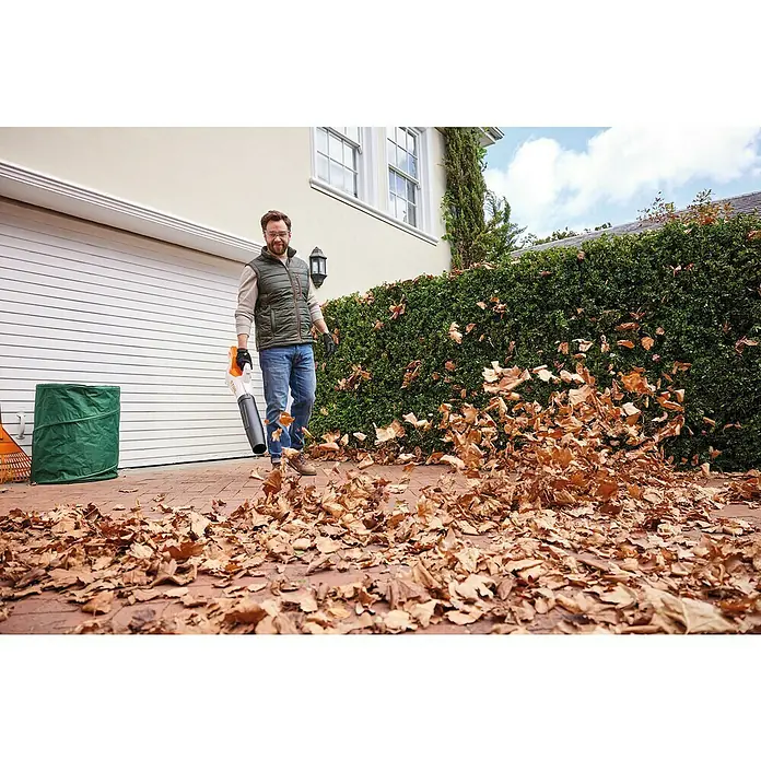 Stihl AK Akku-Laubbläser BGA 50 - 36 V, Ohne Akku, Blasgeschwindigkeit: 55 m/s, Blasleistung: 770 m³/h - Ein Mann benutzt einen Laubbläser, um Blätter zu entfernen. Der STIHL Laubbläser ist ein praktisches Werkzeug für die Gartenarbeit.