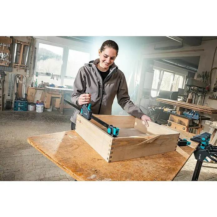 Wolfcraft Einhandzwinge Pro Max - Spannweite: 300 mm, Ausladung: 110 mm - Eine Frau, die eine Wolfcraft Einhandzwinge zum Verleimen eines hölzernen Kasten verwendet.