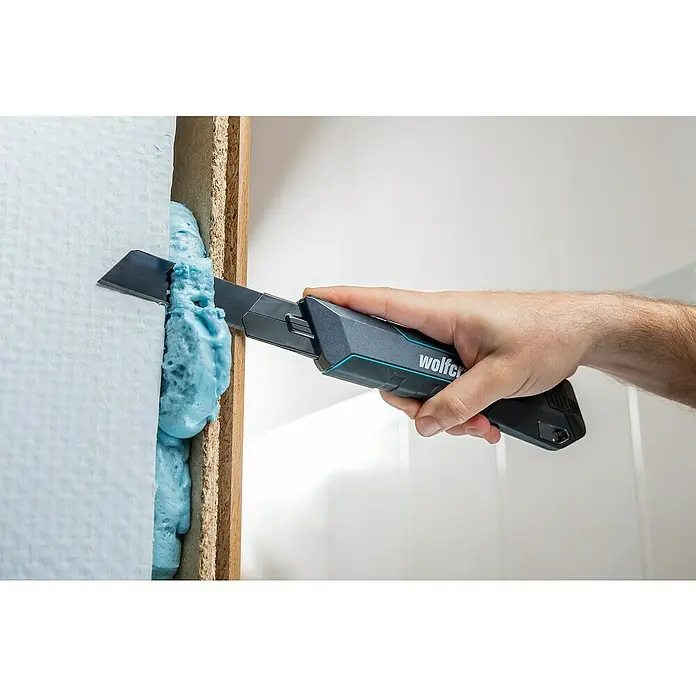 Wolfcraft Cuttermesser Pro Safety - Abbrechklinge, Klingenlänge: 25 mm - Ein Handwerker schneidet Bauschaum mit einem Wolfcraft-Messer zwischen einer Wand und einem Holzrahmen.