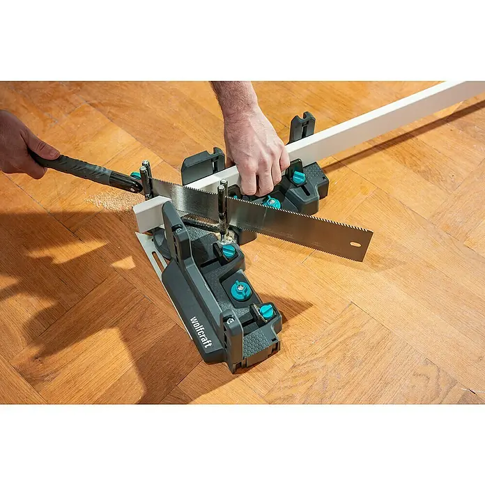 Wolfcraft Gehrungsschneidlade & Schmiege - Kunststoff - Werkzeug: Eine Wolfcraft Kapp- und Gehrungssäge beim Zuschneiden eines weißen Holzstücks auf einem Holzboden.