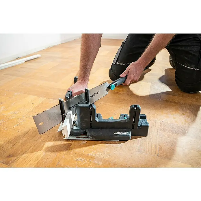 Wolfcraft Japansäge - Blattlänge: 330 mm - Wolfcraft Schneidlade mit Handsäge beim Zuschneiden einer weißen Fußleiste auf einem Holzboden.