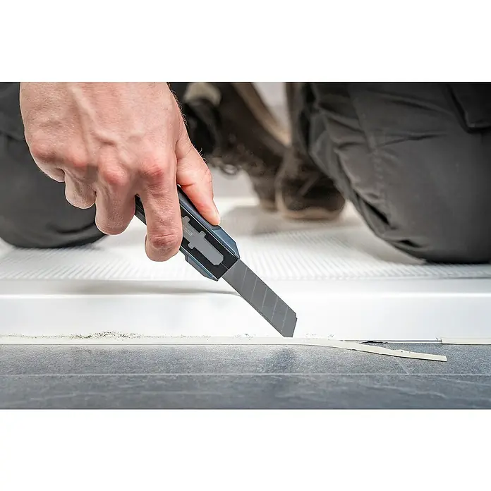 Wolfcraft Schabermesser Dual - Typ Griff: 2K - Das Bild zeigt die Anwendung eines scharfen Cuttermessers, um präzise eine Dichtung zu entfernen oder zu schneiden, was die Messerscharfe des Produkts hervorhebt.