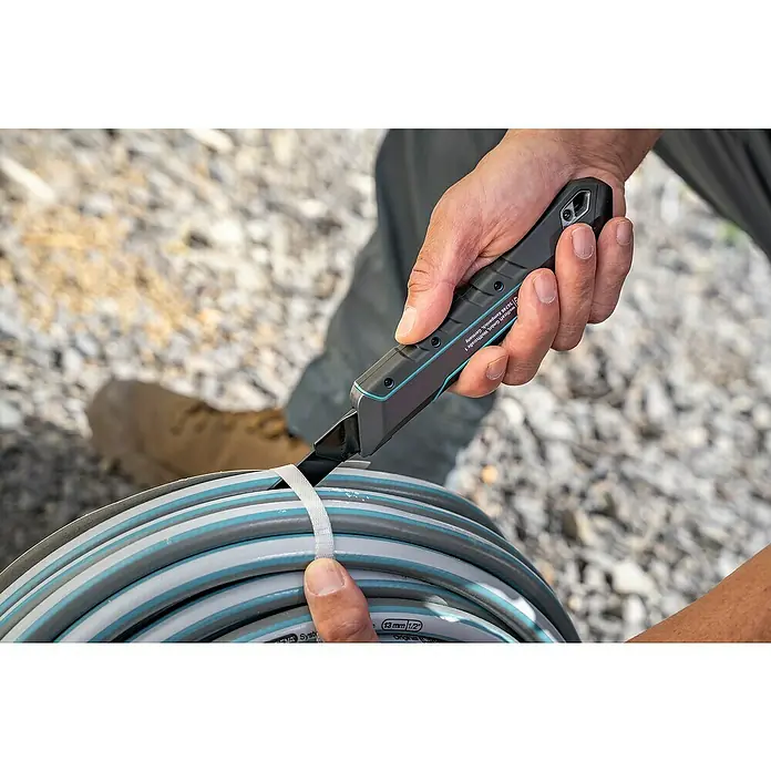 Wolfcraft Cuttermesser Pro Safety - Abbrechklinge, Klingenlänge: 18 mm - Nahaufnahme eines Mannes, der mit einem scharfen Wolfcraft-Messer ein Band um einen grauen Schlauch durchschneidet.