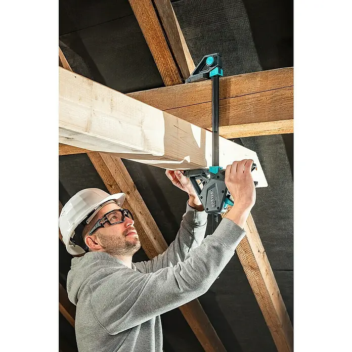 Wolfcraft Einhandzwinge Pro Max - Spannweite: 700 mm, Ausladung: 110 mm - Ein Bauarbeiter befestigt einen Holzrahmen mit einer Wolfcraft Deckenstütze, um eine stabile und sichere Konstruktion zu gewährleisten.