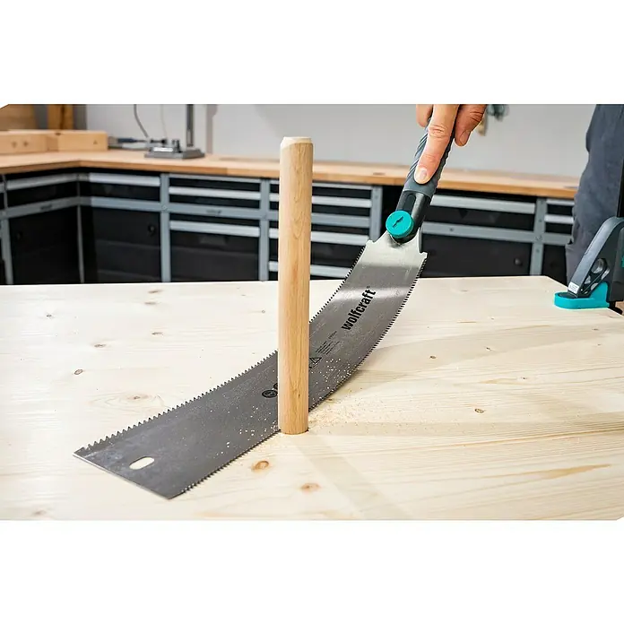 Wolfcraft Japansäge - Blattlänge: 330 mm - Ein Wolfcraft Fuchsschwanz sägt ein Holzrundstück auf einer hellen Holzoberfläche, ideal für Werkstattprojekte.