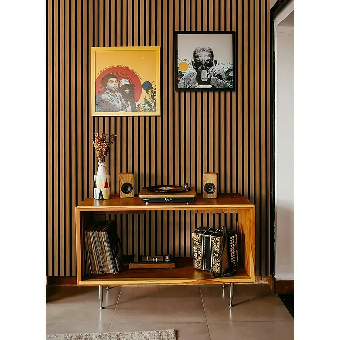 Panel acústico decorativo - 244 x 60,5 x 2,2 cm, Roble - Configuración con un tocadiscos, altavoces, discos y un acordeón sobre un armario de madera con dos imágenes enmarcadas en la pared.