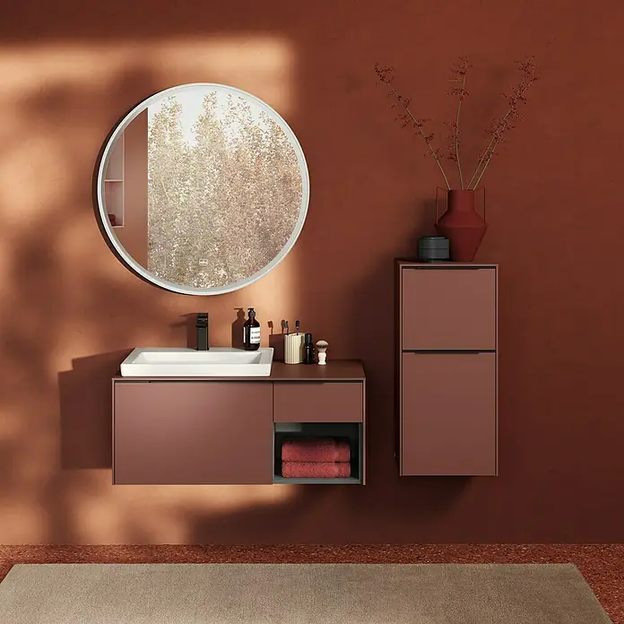 Villeroy & Boch Subway 3.0 Seitenschrank - B x T x H: 40 x 36,2 x 86 cm, Wine Red, DIN Anschlag: Rechts, Farbe Griff: Volcano Black - Ein modernes Badezimmer mit einem braunen Waschtisch, einem runden Spiegel und einer passenden Kommode. Die Farbgebung ist warm und einladend.