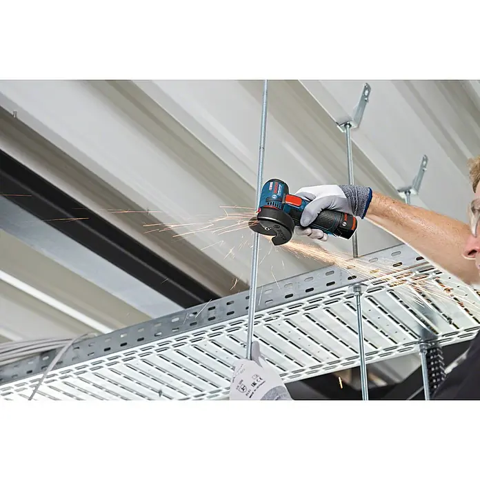 Bosch Professional Akku-Winkelschleifer GWS 12V-76 - Li-Ionen, Ohne Akku, Durchmesser Scheibe: 76 mm, Leerlaufdrehzahl: 19.500 U/min - Akku-Winkelschleifer von Bosch im Einsatz, der Funken sprüht, während er durch eine Metallstange schneidet. Ideal für Handwerker und Bauprojekte.