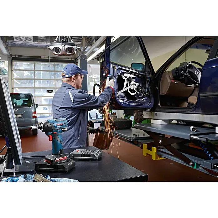 Bosch Professional Akku-Winkelschleifer GWS 12V-76 - Li-Ionen, Ohne Akku, Durchmesser Scheibe: 76 mm, Leerlaufdrehzahl: 19.500 U/min - Ein Bosch Akku-Schlagschrauber auf einem Tisch mit einem Mechaniker, der an einem Auto arbeitet, wobei Funken sprühen.