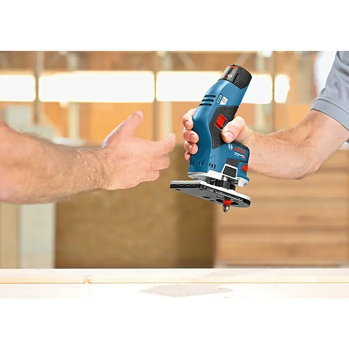 Bosch Professional Akku-Kantenfräser GKF 12V-8 - 12 V, Ohne Akku, Leerlaufdrehzahl: 13.000 U/min - Einhandfräse von Bosch, Modell Professional GKF 12V-8, wird von einer Hand gehalten, während eine andere Hand sich nähert.