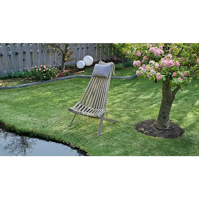 Garden Pleasure Relaxsessel Falun inkl. Kissen - Kiefernholz, Grau, 93 x 69 x 104 cm - Holzliegestuhl mit hellgrauem Kissen, in einem sonnigen Garten neben einem Teich und blühendem Baum.