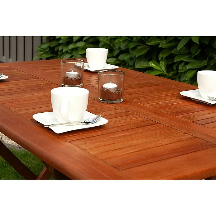 Garden Pleasure Gartentisch Orlando - L x B x H: 120 x 70 x 74 cm, Eukalyptus, Natur, Klappbar - Rotbrauner Holztisch für den Außenbereich, gedeckt mit weißen Tassen und Kerzen.
