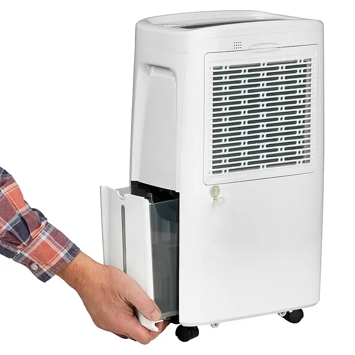 Woods Elektro-Luftentfeuchter MDX 14 - 220 W, Entfeuchtungsleistung: 10 l/Tag, Weiß - Weißer Luftentfeuchter; eine Hand entnimmt den transparenten Wassertank.