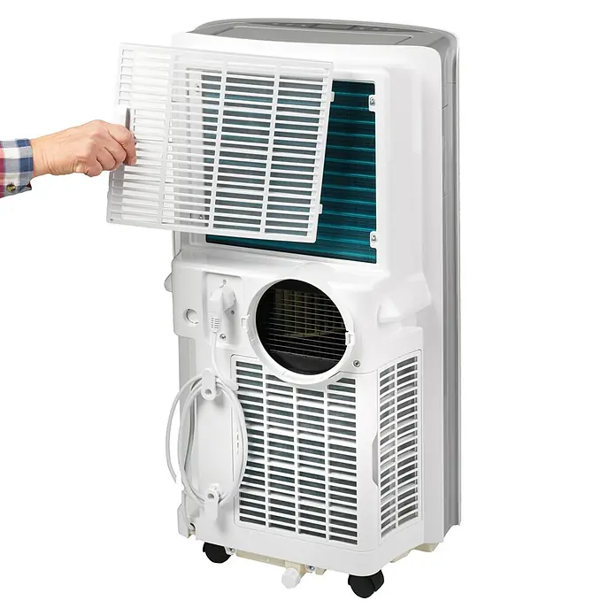 Woods Mobiles Klimagerät Cortina 12K - 3,5 kW, Raumgröße: 35 m², Weiß - Eine Hand öffnet den hinteren Filter eines weißen tragbaren Klimageräts, zeigt blaue Kondensatorlamellen und eine runde Entlüftung.