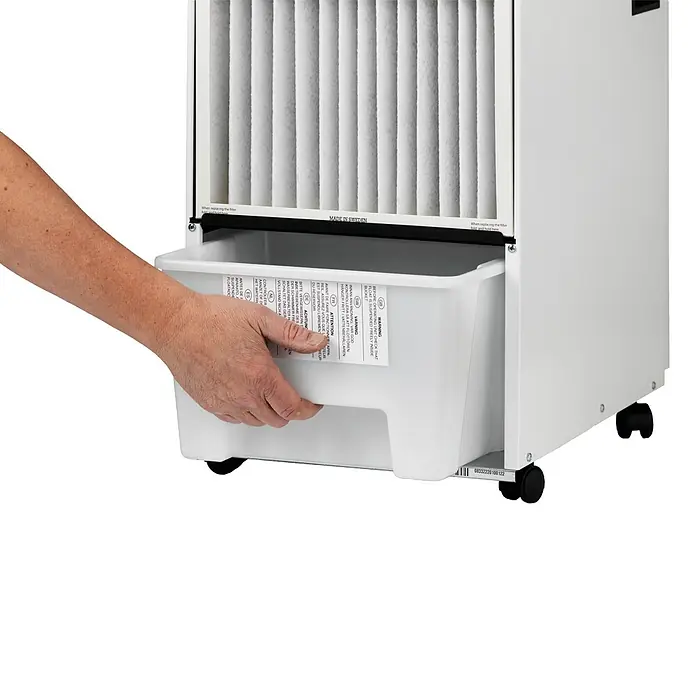 Woods Elektro-Luftentfeuchter SW 22 FW - 190 W, Entfeuchtungsleistung: 13,5 l/Tag, Weiß - Eine Hand zieht einen weißen Kunststoff-Wasserbehälter mit Warnhinweisen aus einem weißen Gerät mit plissiertem Luftfilter.