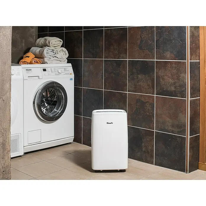 Woods Elektro-Luftentfeuchter MDX 14 - 220 W, Entfeuchtungsleistung: 10 l/Tag, Weiß - Weißer Wood's Luftentfeuchter auf Fliesenboden neben einer Waschmaschine im Waschraum.