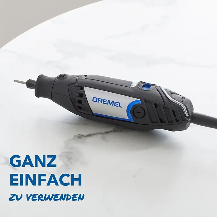 Dremel Multifunktionswerkzeug 3200 (1/90) - 130 W - Eine Nahaufnahme eines Dremel Multifunktionswerkzeugs, das auf einer weißen Marmoroberfläche liegt. Es ist ein kabelloses Werkzeug mit verschiedenen Aufsätzen.