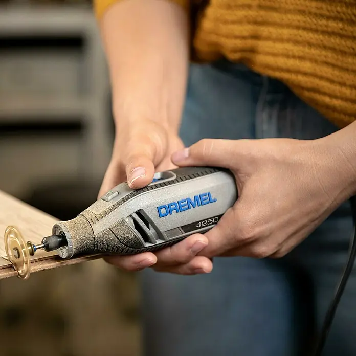 Dremel Multifunktionswerkzeug 4250 (4250 Platinum+) - 175 W, Leerlaufdrehzahl: 5.000 U/min - 35.000 U/min - Nahaufnahme eines Dremel 4250 Multifunktionswerkzeugs beim Schneiden eines Holzstücks, das Präzision und Vielseitigkeit zeigt.