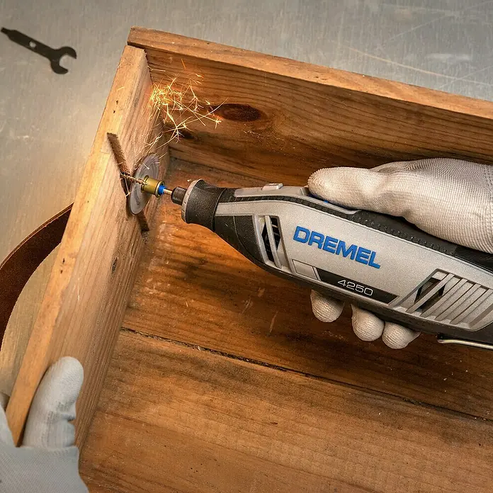 Dremel Multifunktionswerkzeug 4250 (4250 Platinum+) - 175 W, Leerlaufdrehzahl: 5.000 U/min - 35.000 U/min - Nahaufnahme eines Dremel 4250 Multifunktionswerkzeugs beim Schneiden eines Holzstücks, wobei Funken entstehen.