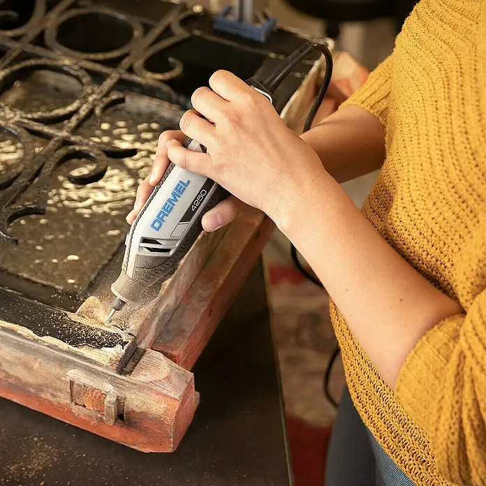 Dremel Multifunktionswerkzeug 4250 (4250 Platinum+) - 175 W, Leerlaufdrehzahl: 5.000 U/min - 35.000 U/min - Nahaufnahme einer Person, die mit einem Dremel 4250 Multifunktionswerkzeug an einem Holzrahmen arbeitet.