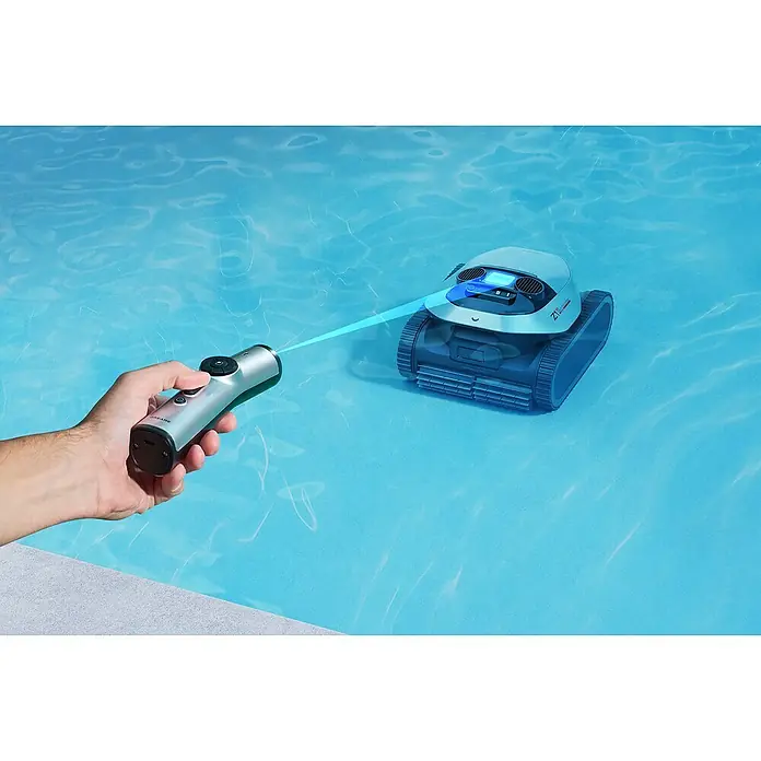 Dreame Poolroboter Z1 Pro - Akkubetrieben, Passend für: Pools bis 200 m² Grundfläche, Filterleistung: 30.000 l/h - Eine Hand steuert eine silberne Fernbedienung, die einen blauen Lichtstrahl auf einen Poolroboter in einem klaren blauen Schwimmbecken richtet.