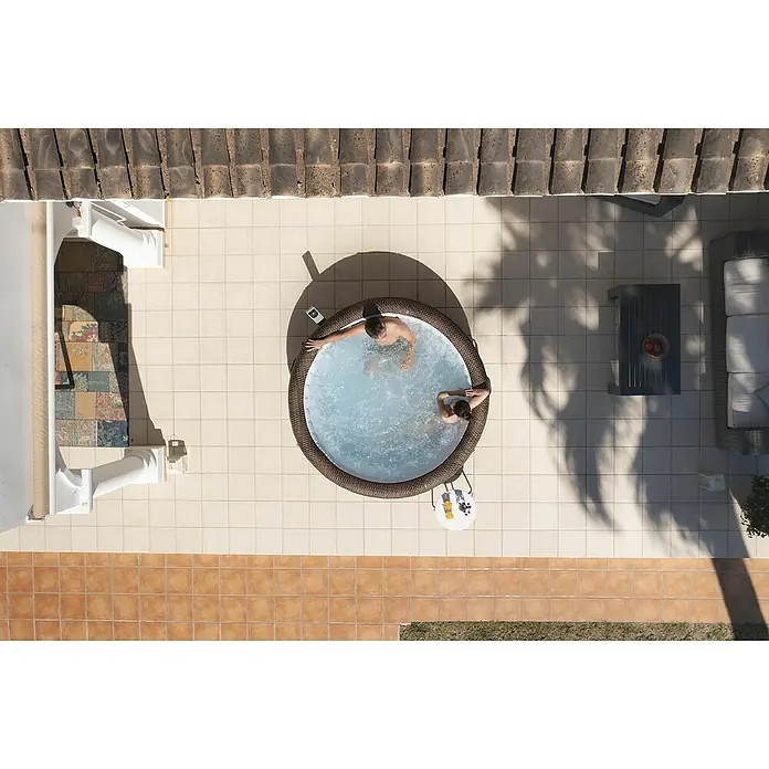 Bestway Lay-Z-Spa Mobil-Whirlpool Bali - Ø x H: 216 x 71 cm, Braun, 1.260 l - Luftaufnahme eines aufblasbaren Whirlpools mit zwei Personen, umgeben von hellen Fliesen und Außenmöbeln.