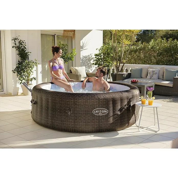 Bestway Lay-Z-Spa Mobil-Whirlpool Bali - Ø x H: 216 x 71 cm, Braun, 1.260 l - Ein Lay-Z-Spa Bali Whirlpool im Freien, in dem ein Paar entspannt. Der aufblasbare Pool in Rattan-Optik bietet Platz für erholsame Stunden.