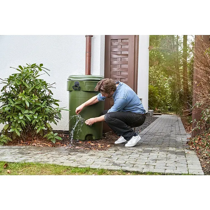 Tesa Ultra Power Reparaturband Under Water - 1,5 m x 50 mm, Transparent - Ein Mann befüllt eine Gießkanne mit Regenwasser aus einer grünen Regentonne im Garten, umweltfreundliche Wassernutzung.