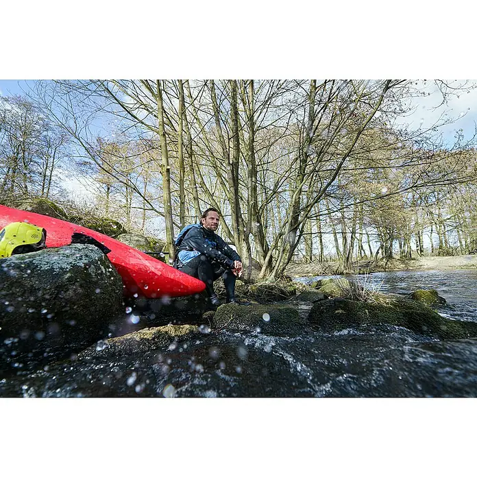 Tesa Ultra Power Reparaturband Under Water - 1,5 m x 50 mm, Transparent - Mann sitzt neben seinem roten Kajak am Flussufer, bereit für das nächste Abenteuer. Helm liegt daneben bereit.