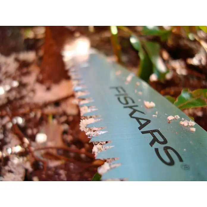 Fiskars Hand-Astsäge SW84 - Länge: 54,3 cm, Max. Aststärke: 12 mm, Orange/Schwarz - Nahaufnahme einer Fiskars-Gartensäge mit Sägespänen auf der Klinge, ideal für präzise Gartenarbeiten und Baumschnitt.