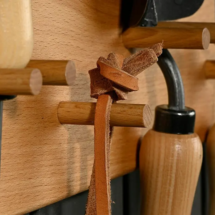Dobar Gerätehalter klein - L x B x H: 36 x 6 x 10 cm, Rotbuche, Natur - Detailaufnahme einer hölzernen Werkzeugleiste mit Lederband, das um einen Stift geknotet ist. Perfekt zur Aufbewahrung von Werkzeugen.