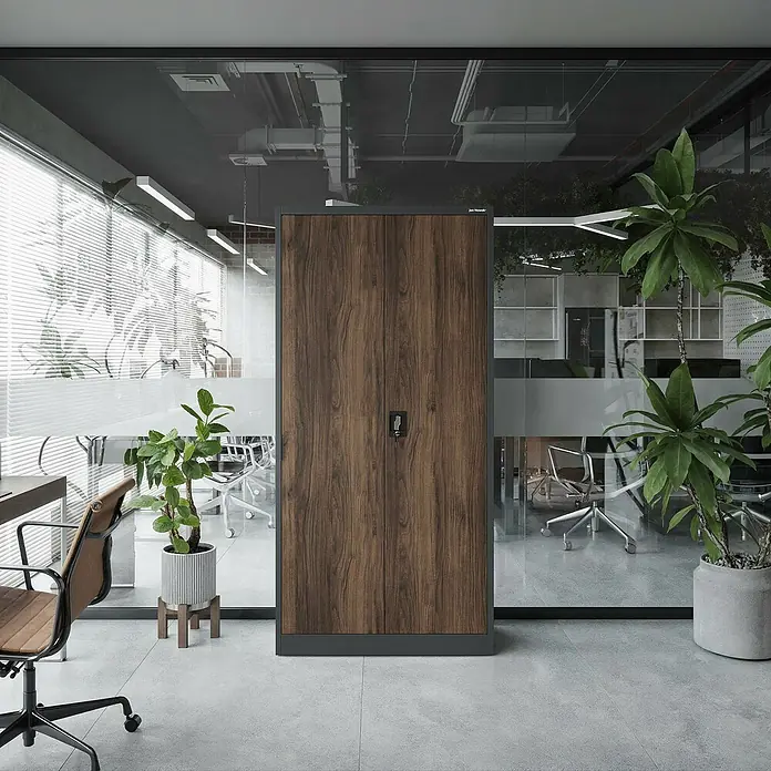 Jan Nowak Aktenschrank Jan - B x T x H: 90 x 40 x 185 cm, Anthrazit/Nussbaum - Hoher Schrank aus dunklem Holz mit schwarzem Rahmen und Schloss, platziert in einem modernen Büro neben grünen Pflanzen.