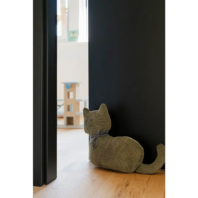 Türstopper - Katze, 33 x 10 x 25 cm - Grüner Kord-Katzen-Türstopper hält eine dunkle Tür auf hellem Holzfußboden offen und blickt in einen Raum.