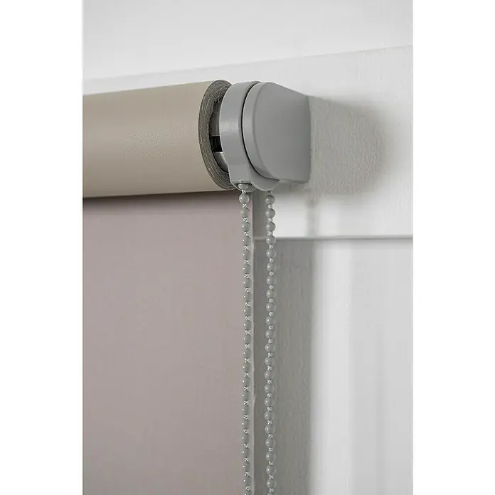 Estor enrollable opaco NDC - An x Al: 90 x 250 cm, Taupé - Primer plano de un estor enrollable beige con un mecanismo de control de cadena gris, montado contra una pared blanca.