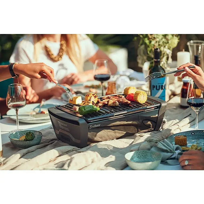 Enders Elektrogrill Aurora - MIrror-Schwarz, Grillfläche (B x T): 37 x 25 cm - Kompakter schwarzer Elektrogrill auf einem Tisch, der Fleisch und Gemüse bei einem Treffen im Freien gart.