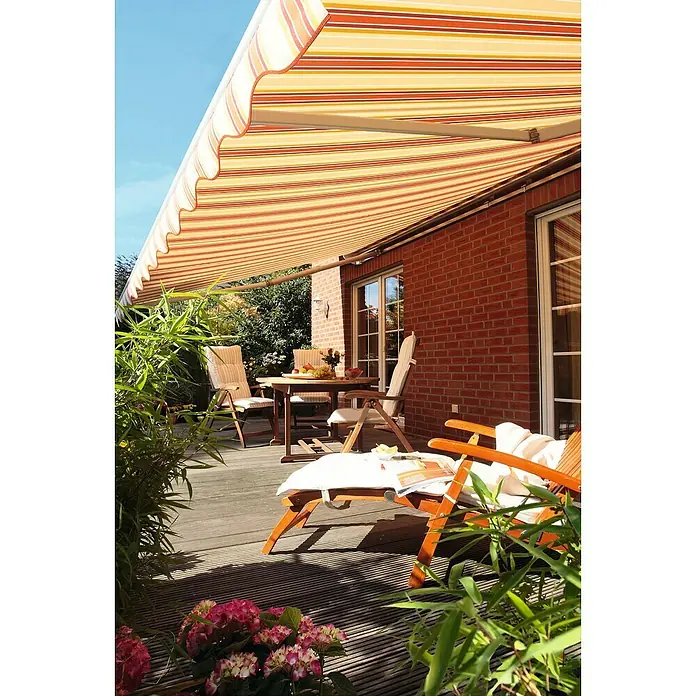 Spettmann Gelenkarmmarkise Star Fix 5996 - Rot/Gelb, Farbe Gestell: Weißaluminium, Breite: 3 m, Ausfall: 2 m - Markise mit orangefarbenen, gelben und weißen Streifen überspannt eine sonnige Holzterrasse und spendet Schatten für Gartenmöbel.