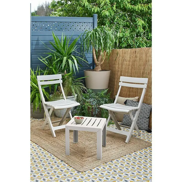 Grosfillex Garten-Beistelltisch Miami - L x B x H: 40 x 40 x 35 cm, Polypropylen, Stapelbar, Rechteckig, Beige - Zwei weiße Klappstühle und ein passender kleiner Tisch auf einer Terrasse.
