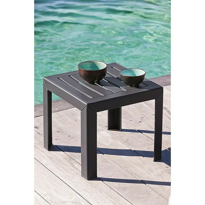 Grosfillex Garten-Beistelltisch Miami - L x B x H: 40 x 40 x 35 cm, Polypropylen, Stapelbar, Quadratisch, Anthrazit - Dunkelgrauer quadratischer Outdoor-Beistelltisch mit Lattenrostplatte, darauf zwei braun-türkise Schalen, auf Holzterrasse am Wasser.