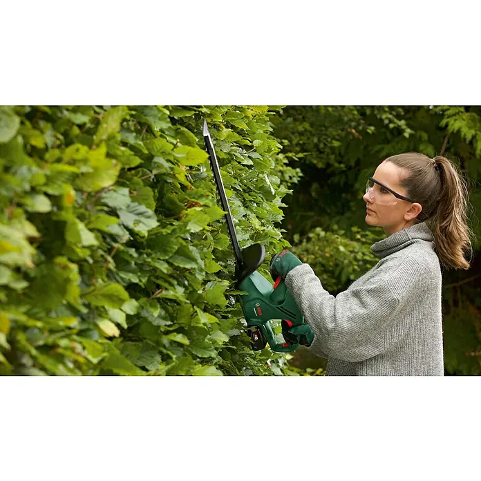 Bosch Power for All 18V Akku-Heckenschere EasyHedgeCut 18V-52-13 - 18 V, Li-Ionen, Ohne Akku - Eine Frau benutzt eine Bosch Heckenschere, um eine Hecke zu schneiden. Die Heckenschere ist grün und schwarz mit einer langen Klinge.