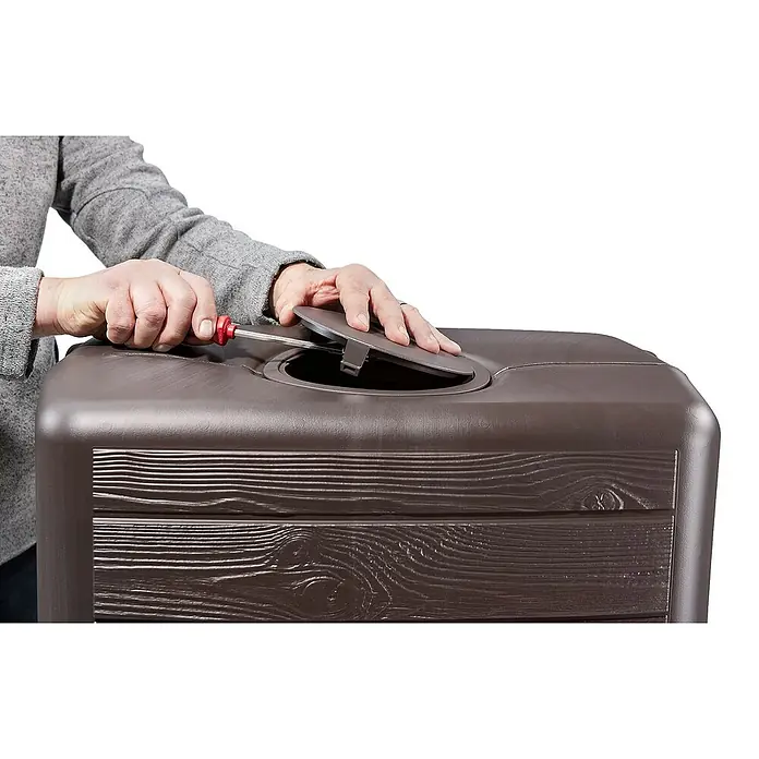 4rain Regenspeicher Slim Wood - 350 l, Dunkelbraun, 1 Stk. - Nahaufnahme eines braunen Pflanzgefäßes mit Holzstruktur, bei dem eine Person mit einem Schraubenzieher einen Deckel befestigt.