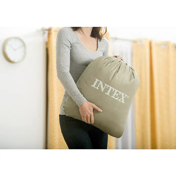 Intex Luftbett Reisebett für Kinder - L x B x H: 168 x 107 x 25 cm, Hellblau, Sicherheitsventil - Eine Frau hält eine olivgrüne Intex-Tasche mit weißem Logo. Die Tasche ist groß und gefüllt, ideal für Campingausrüstung.
