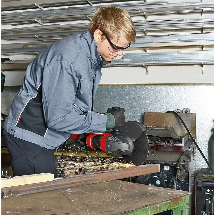 Einhell Expert Elektro-Winkelschleifer TE-AG 230/2000 - 2.000 W, 230 mm, Leerlaufdrehzahl: 6.500 U/min - Ein Handwerker, mit Schutzbrille und Gehörschutz, der mit einem Winkelschleifer ein Metallstück bearbeitet, wobei Funken sprühen.