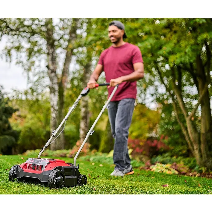Einhell Power X-Change 18V Akku-Vertikutierer-Lüfter GC-SC 18/28 DS LI - Anzahl Akkus: Ohne Akku, 18 V, Arbeitsbreite: 28 mm - Ein Mann mäht Gras mit einem rot-schwarzen Akku-Rasenmäher.