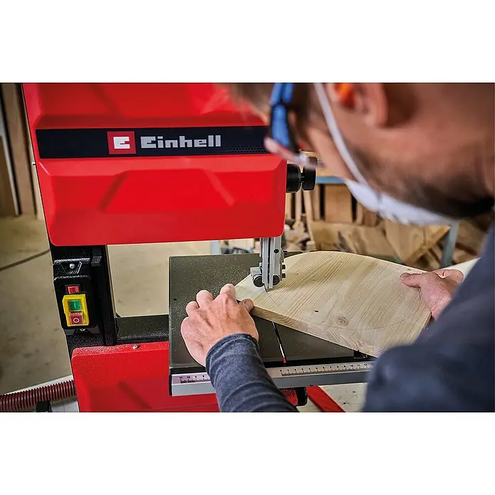 Einhell Expert Bandsäge TC-SB 245 L - 400 W, Leerlaufdrehzahl: 1.450 U/min, Sägebandlänge: 1.712 mm - Ein Mann benutzt eine Einhell Bandsäge, um ein Holzstück zu bearbeiten. Die rote Bandsäge steht im Fokus, während der Mann sie bedient.