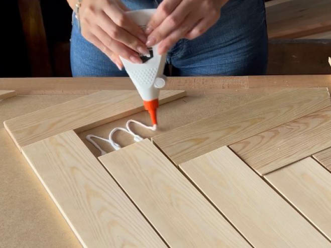 Mit Holzleim werden kleine Leisten auf die MDF-Platte geklebt, sodass ein Fischgrät Design entsteht