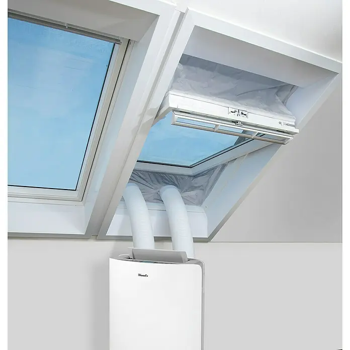 Woods Fensterabdichtung Dachfenster Thermo-Plus für mobile Klimageräte von Woods - Silber, Breite: 38 mm - Weißes mobiles Klimagerät mit zwei weißen Schläuchen, die durch ein abgedichtetes Dachfenster in einem Dachzimmer entlüften.